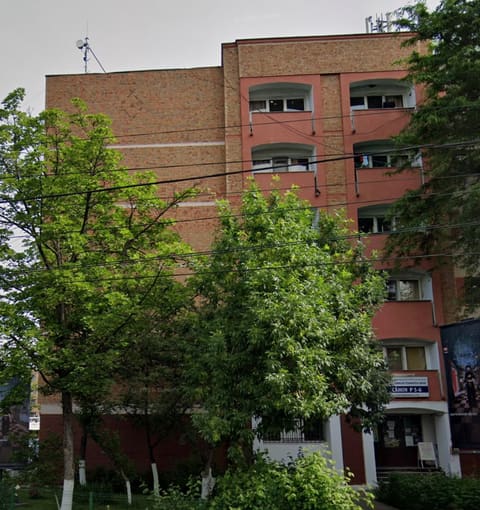 Fațada căminului, o clădire de cărămidă cu balcoane, văzută din stradă. În dreapta jos se vede intrarea, cu firma „Cămin P5-6” deasupra ușii.